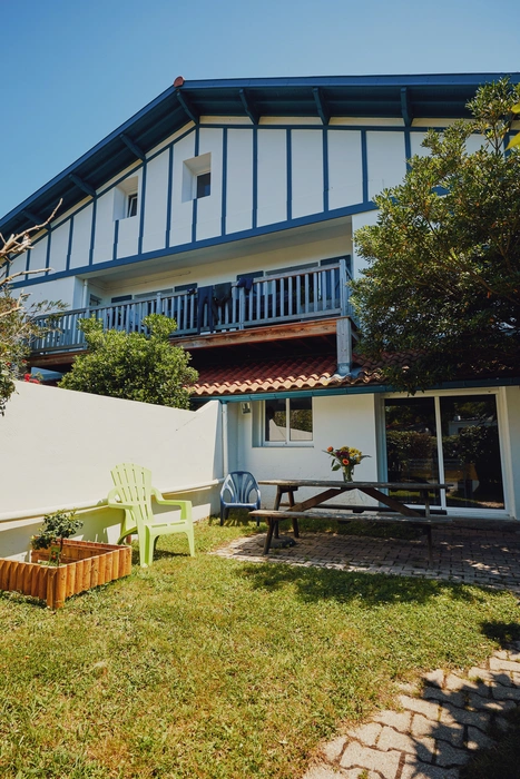 Maison à patio verdoyant et terrasse ensoleillée.