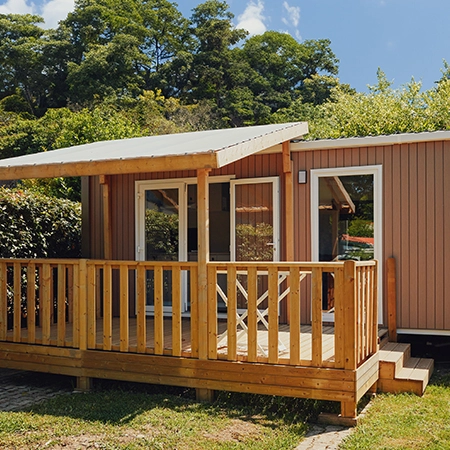 Chalet con terraza de madera, rodeado de vegetación.
