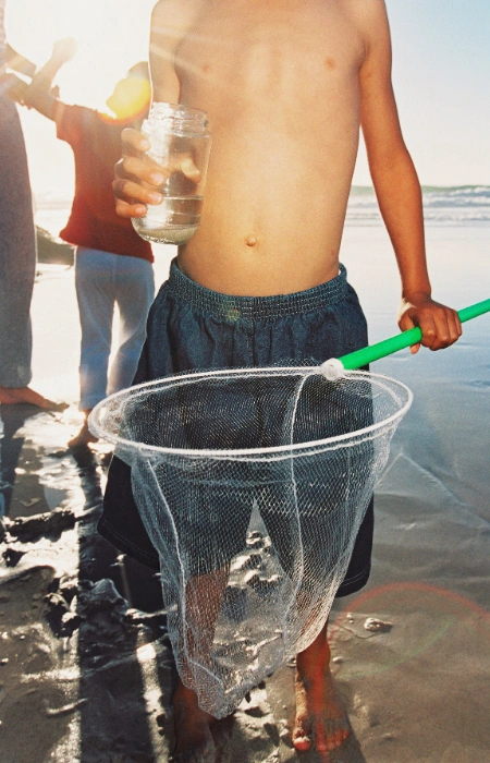 Niño recogiendo agua en la playa.